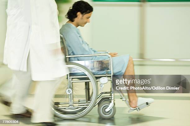 medical staff pushing man in wheelchair, blurred motion - surgical footwear stock pictures, royalty-free photos & images