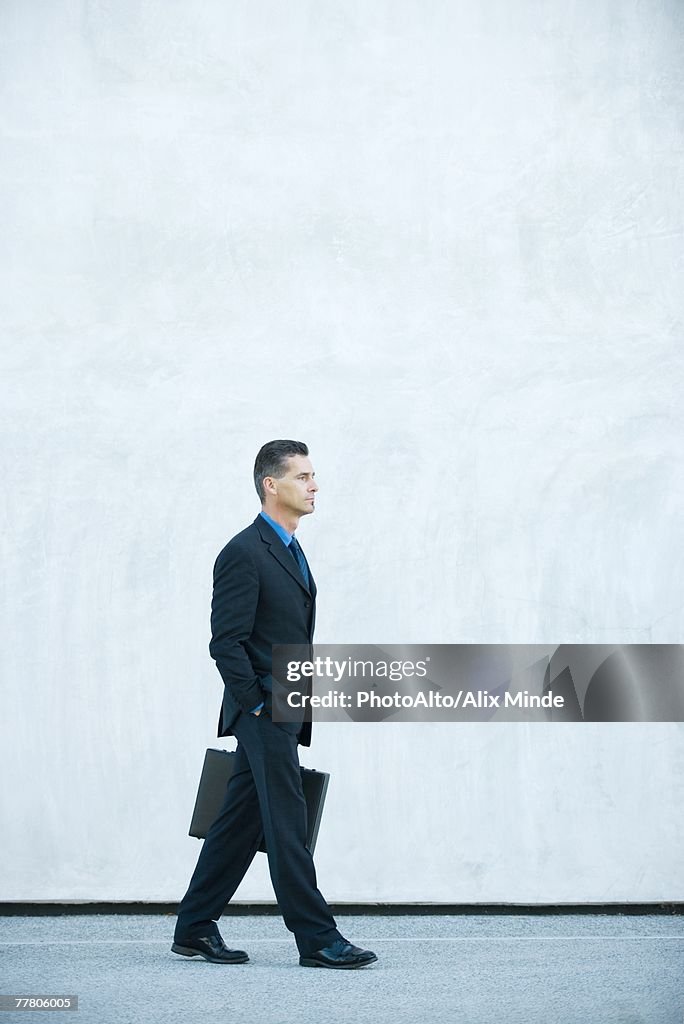 Businessman carrying briefcase, hand in pocket, full length