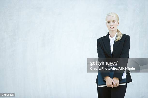 young businesswoman standing, looking at camera, three quarter length - three quarter front view stockfoto's en -beelden