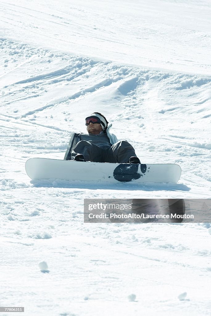 Young snowboarder sitting on the ground, fallen