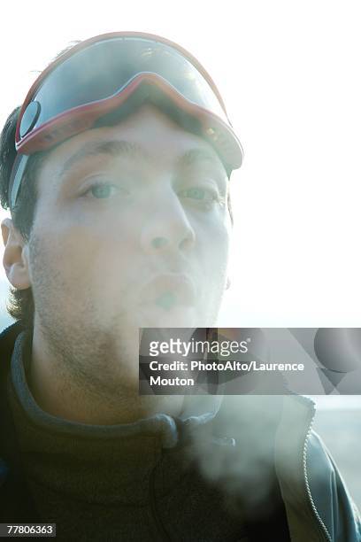 young man breathing out into cold air - fresh air breathing stockfoto's en -beelden