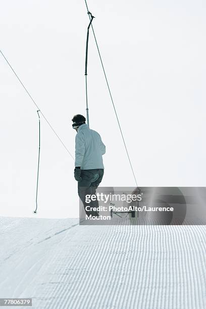 young skier riding ski lift, rear view - tellerlift stock-fotos und bilder