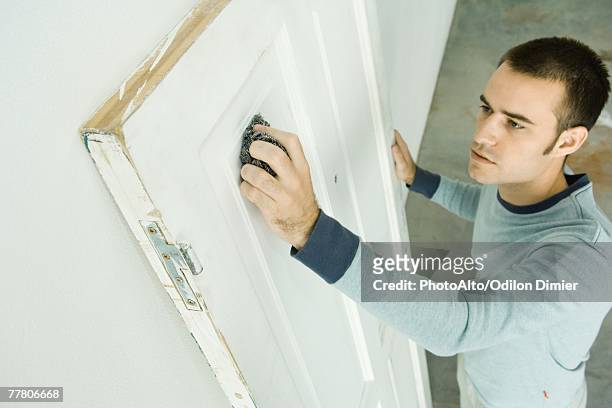 man using scouring pad on door, high angle view - brillos stockfoto's en -beelden