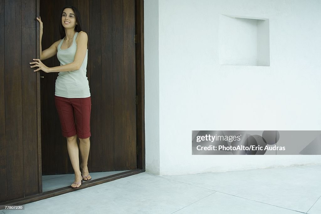 Woman standing in doorway, full length portrait