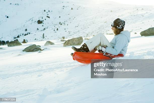 teenage girl riding sled on ski slope, side view, full length - girl sitting with legs open stock pictures, royalty-free photos & images