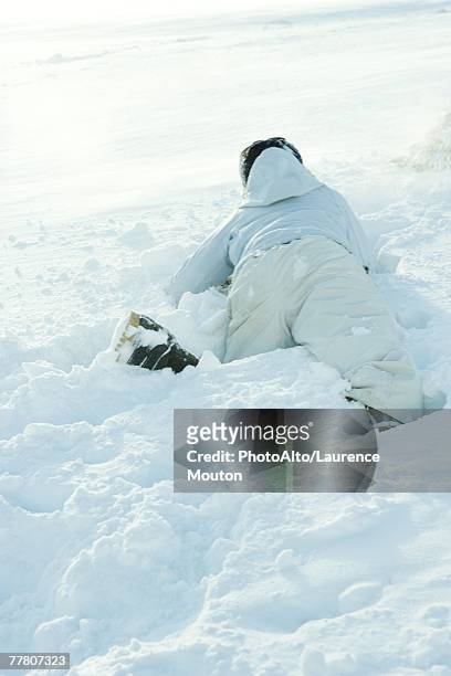 young person lying on stomach in snow, fallen, rear view - northern european descent ストックフォトと画像