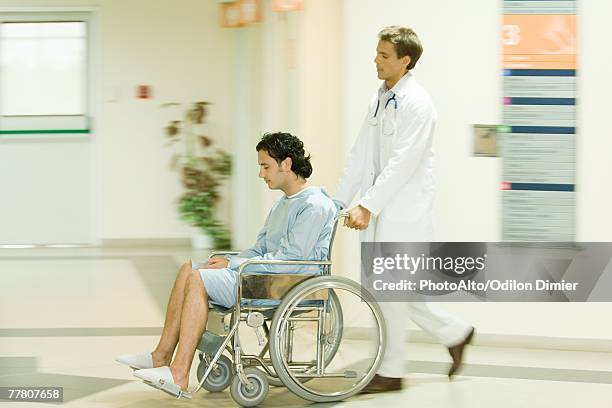 male doctor pushing man in wheelchair, full length - surgical footwear stock pictures, royalty-free photos & images