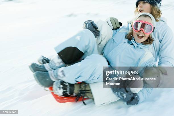 two young friends riding sled together, blurred motion - skischoen stockfoto's en -beelden