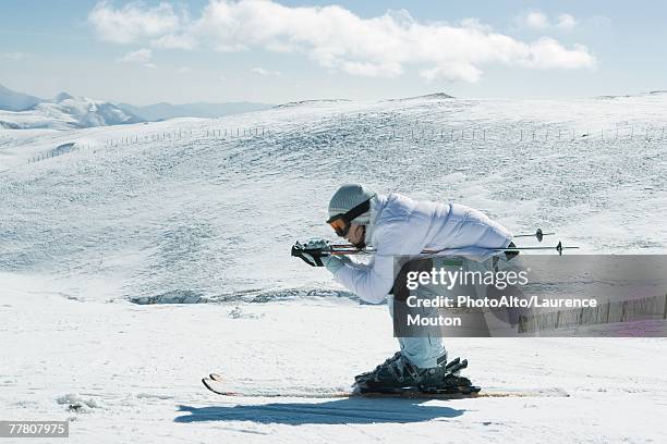 young female skier crouching, side view, full length portrait - ski boot stock pictures, royalty-free photos & images
