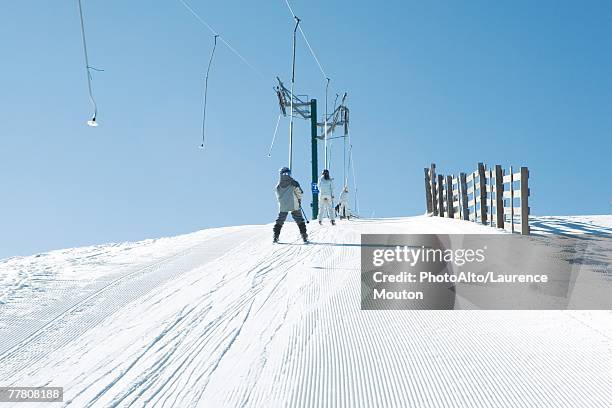 young skiers going up hill on ski lift, rear view - tellerlift stock-fotos und bilder