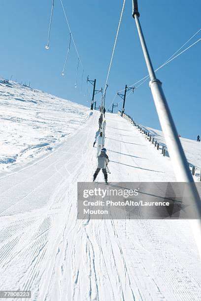 young skiers using ski lift on ski slope, low angle view - tellerlift stock-fotos und bilder
