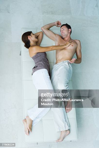 couple lying on chaise longue together, woman pushing man away, full length, view from above - chaise longue stock pictures, royalty-free photos & images