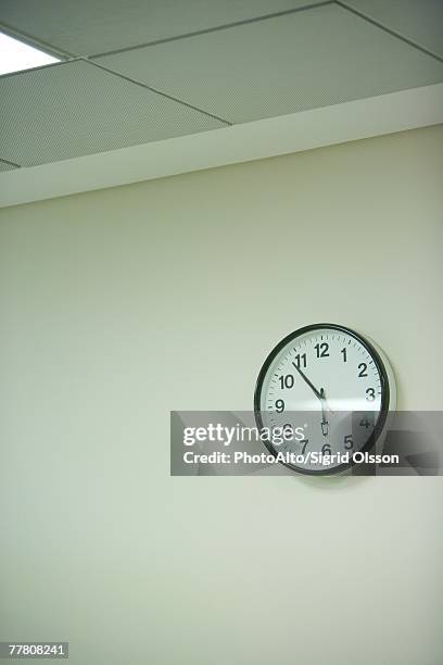 clock hanging on wall under fluorescent light - horloge murale photos et images de collection