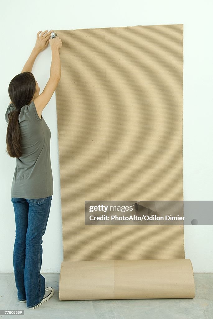 Woman stapling corrugated cardboard to wall