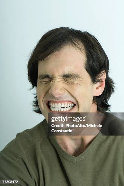 man closing eyes and clenching teeth, portrait - cerrando os dentes - fotografias e filmes do acervo