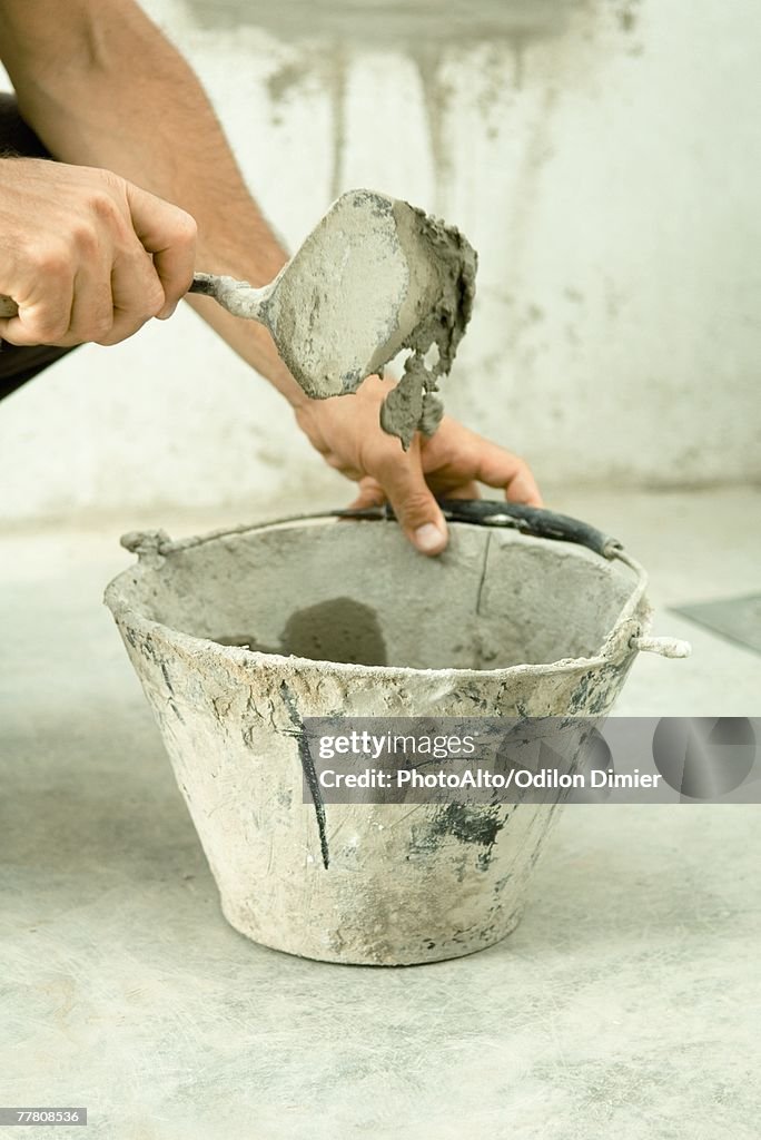 Man holding trowel over bucket, close-up of hands