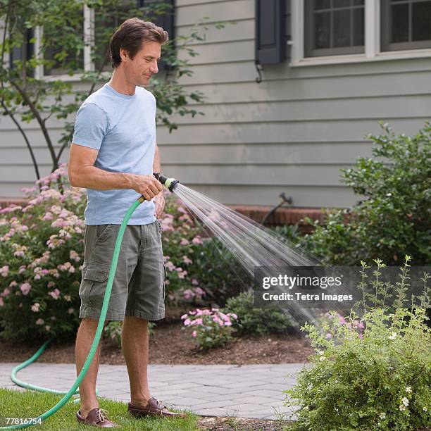 man watering plants - hose stock pictures, royalty-free photos & images