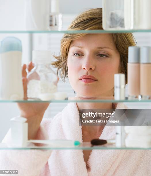 woman looking in medicine cabinet - beauty cabinet stock pictures, royalty-free photos & images