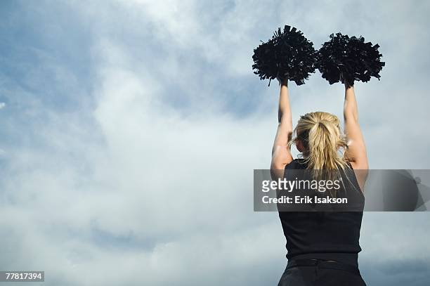 rear view of cheerleader with pom poms - cheerleading stock-fotos und bilder