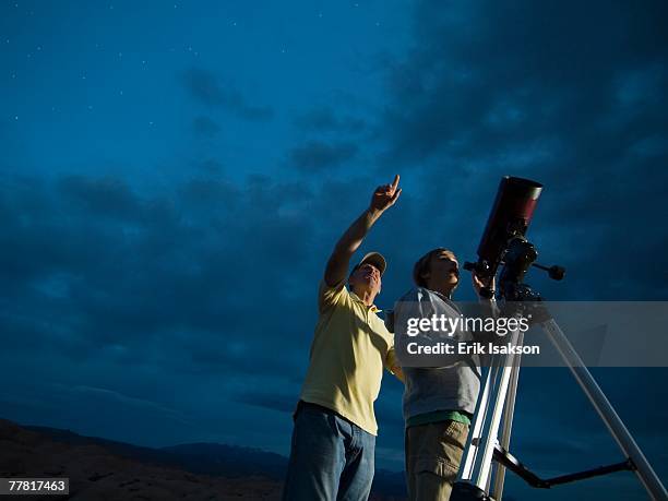 couple using telescope on tripod - astronomy photos et images de collection