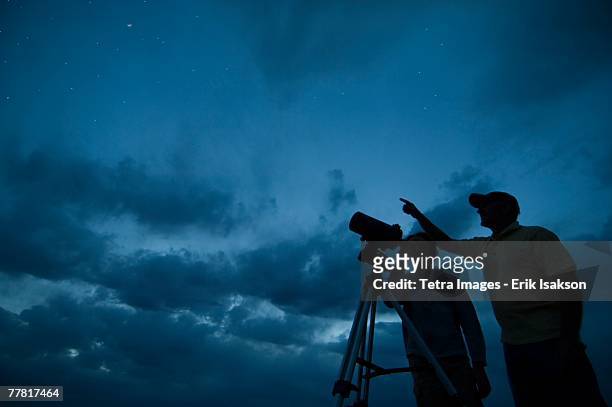 couple using telescope on tripod - astronomia foto e immagini stock