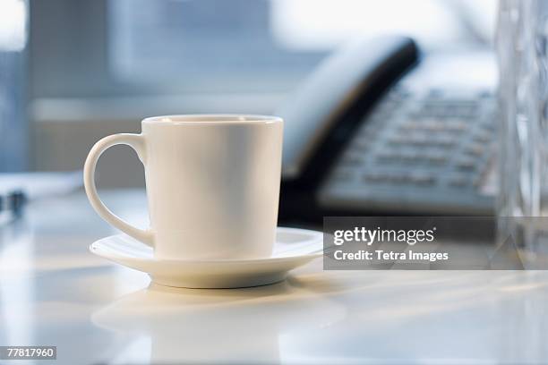 coffee mug and saucer on desk - pires imagens e fotografias de stock