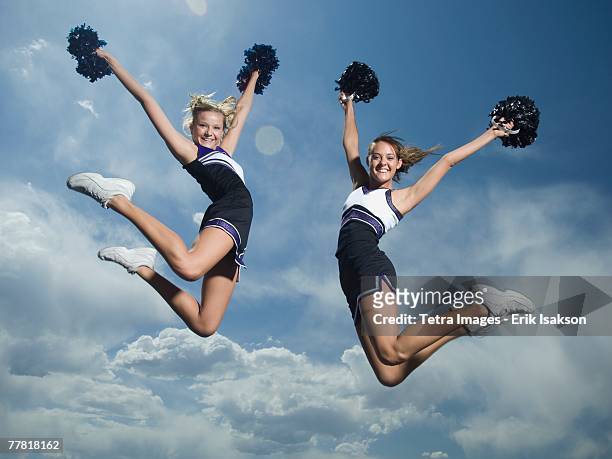 cheerleaders with pom poms jumping - cheerleading stock-fotos und bilder
