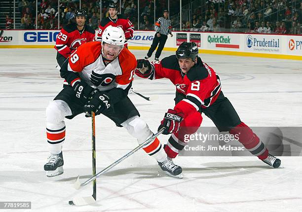 Scott Hartnell of the Philadelphia Flyers tries to control the puck against Sheldon Brookbank of the New Jersey Devils at the Prudential Center...