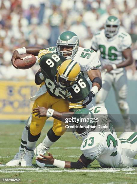 Ed West, Tight End for the Green Bay Packers is tackled by Philadelphia Eagles Linebackers Seth Joyner and William Frizzell during their National...