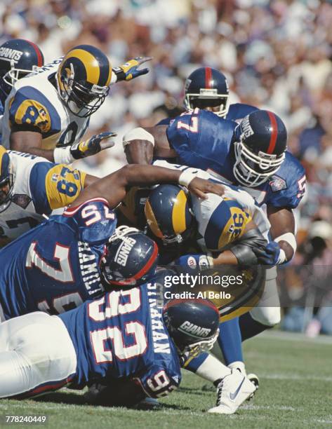 Jerome Bettis, Running Back for the Los Angeles Rams is tackled by Corey Miller, Michael Strahan and Keith Hamilton of the New York Giants as he...