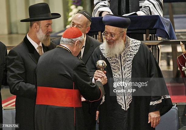 Cologne's Cardinal Joachim Meisner hands over the decoration for a Torah roll to Rabbi Shlomo Moshe Amar as Chief Rabbi Yona Metzger looks on during...