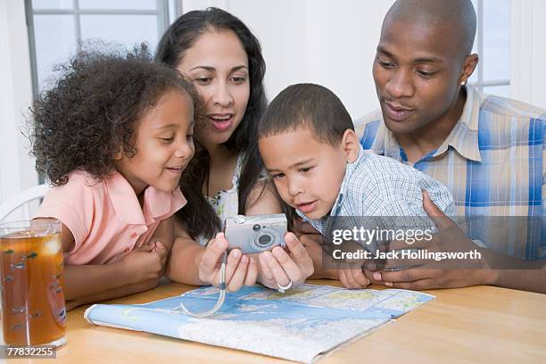 young couple looking at a digital camera with their son and daughter - ice cube family stock pictures, royalty-free photos & images