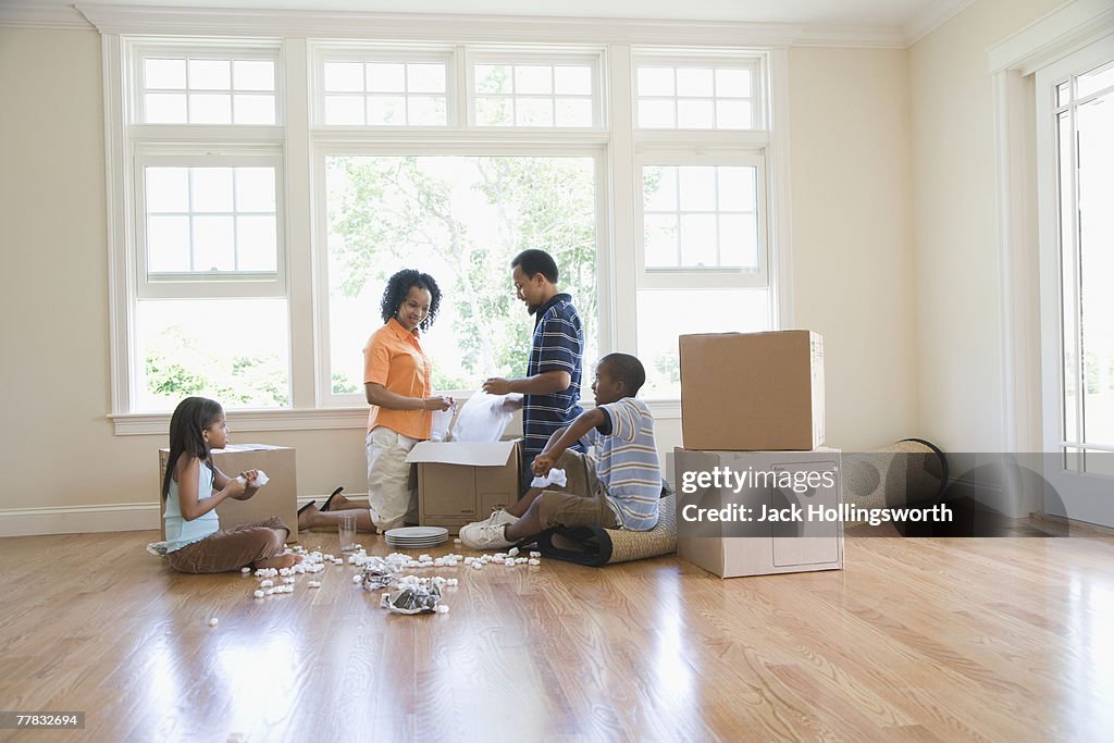 Side profile of a boy and a girl unpacking a cardboard box with their parents