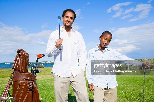 portrait of a young man and his son holding golf clubs - jack of clubs photos et images de collection