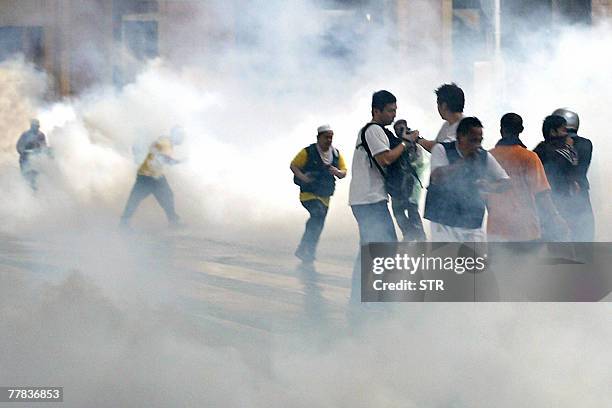 Disoriented demonstrators run for cover as riot police disperse tear gas in the Masjid Jamek area of downtown Kuala Lumpur, 10 November 2007....