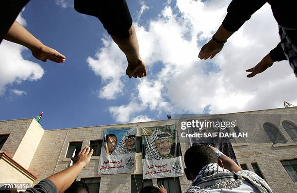 Palestinian students raise their hands towards a portrait of late leader Yasser Arafat at the Arab-American University near the West Bank town of...