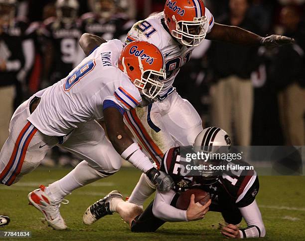 Blake Mitchell of the South Carolina Gamecocks is tackled by Carlos Dunlap and Derrick Harvey, #91 of the Florida Gators at the Williams-Brice...