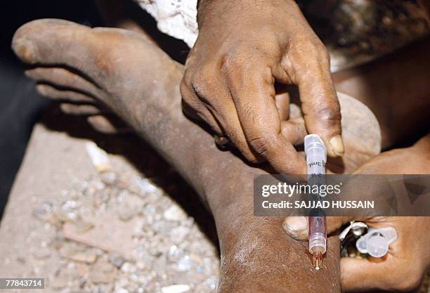 An Indian man receives a drug injection on the road side in Mumbai late 10 November 2007. Drug addiction has become a major health problem in India...