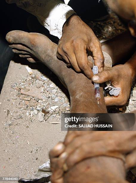 An Indian man receives a drug injection on the road side in Mumbai late 10 November 2007. Drug addiction has become a major health problem in India...