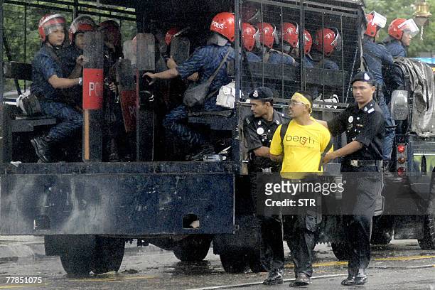 An arrested demonstrator is led away by police officers in the Masjid Jamek area of downtown Kuala Lumpur, 10 November 2007. Malaysian police...