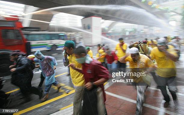 Demonstrators run for cover as riot police fire water cannon into the crowd in the Masjid Jamek area of downtown Kuala Lumpur, 10 November 2007....