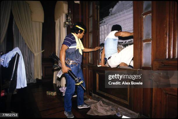 Plain-clothes policeman expels a looter from the presidential office at Malacanang Palace, Manila, on the night President Ferdinand Marcos and his...