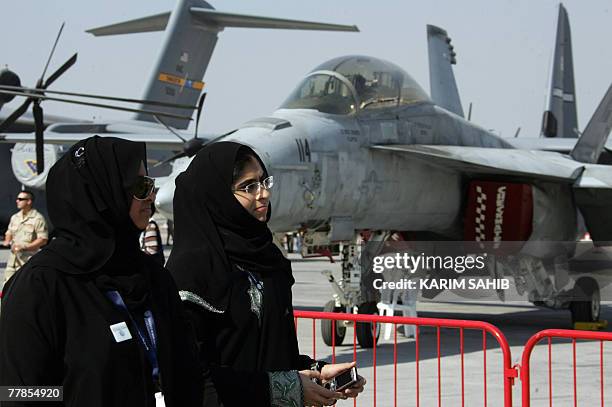 Emirati women pass next to a displayed US Air Force F-18 Hornet fighter jet during the 2nd day of the 2007 Dubai Airshow at Dubai airport, 12...