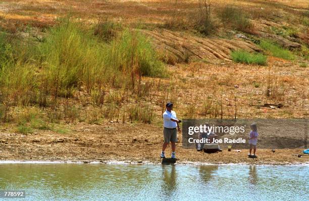 Family enjoys an afternoon of lakeside fishing from a spot that not too long ago was underwater September 6, 2000 near Dallas, Texas. The drought...