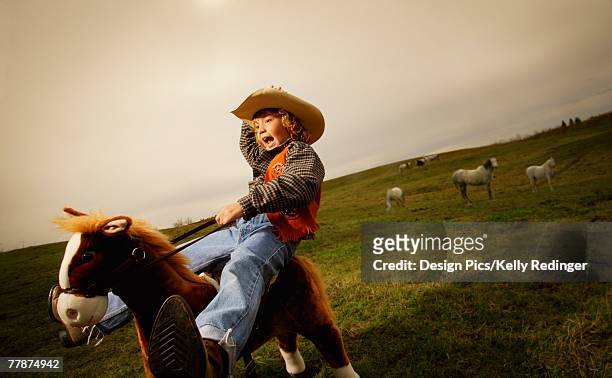 young boy playing on pretend horse - cowboy costume stock-fotos und bilder