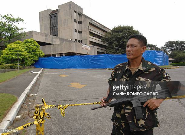 An armed soldier guards the sealed damaged southern section of the House of Representatives in Manila, 14 November 2007 following a bomb attack that...