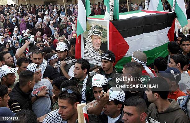 Palestinian Fatah supporters carry a mock coffin covered with Palestinian flags and a portrait of late leader Yasser Arafat during a rally against...
