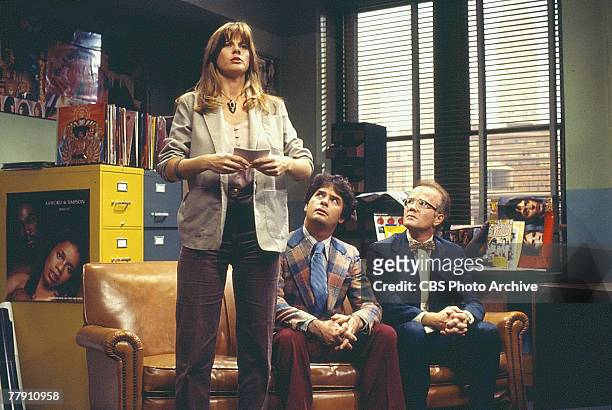 American actress Jan Smithers stands and reads from a handful of index cards, watched by Frank Bonner and Richard Sanders , in a scene from an...
