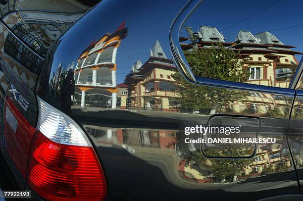 Roma gypsys houses are seen the reflection of a luxury car the village of Buzescu, 110 kms west orom Bucharest, 13 November 2007. Unlike other...