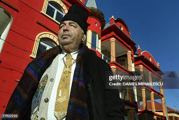 Roma gypsy Marin Stoica poses with his gold tie in front of gypsy houses in the village of Buzescu, 110 kms west orom Bucharest, 13 November 2007....
